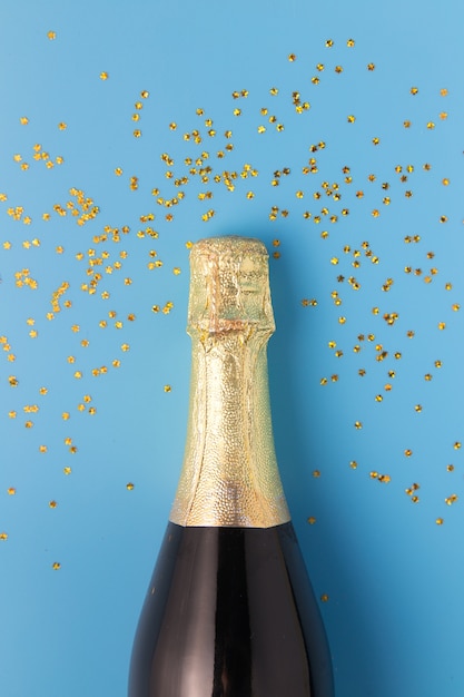 Lay plat de fête, bouteille de champagne sur fond bleu avec des paillettes.