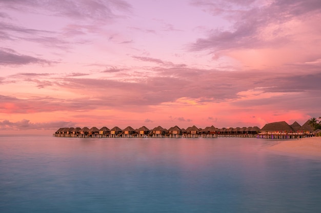 Île des Maldives, complexe de villas de luxe sur l'eau et jetée en bois. Beau ciel et nuages et plage