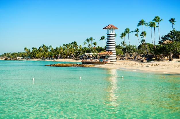 Île tropicale paradisiaque en République dominicaine. Sable blanc, mer bleue, ciel clair et phare à terre