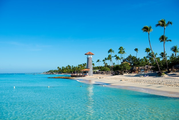 Île tropicale paradisiaque en République dominicaine. Sable blanc, mer bleue, ciel clair et phare à terre