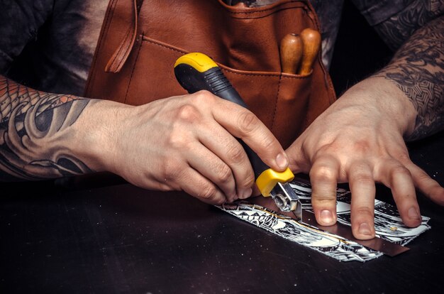 Leather Tanner Est Passionné Par Son Entreprise Dans L'atelier De Cuir. Artisan Découpant Des Formes De Cuir Pour Un Nouveau Produit à Son Bureau.