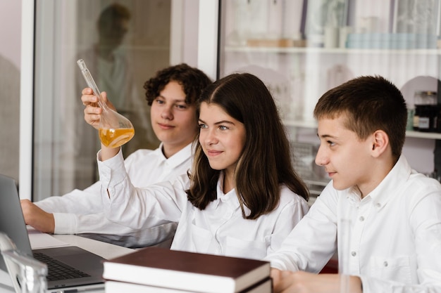 Leçon de chimie Une écolière et ses camarades de classe tiennent une fiole pour des expériences et des sourires dans le laboratoire