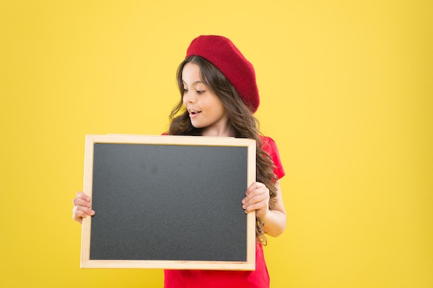 Leçon intéressante grande vente enfant sur mur jaune retour à l'école Informations intéressantes tableau d'information Nouvelles de la mode fille heureuse en béret français petite fille enfant avec espace de copie de panneau d'école