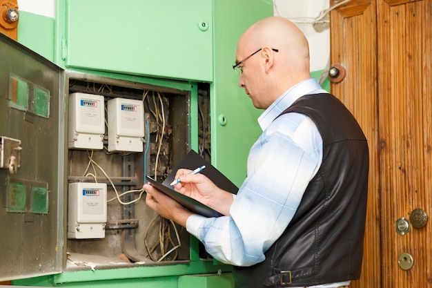 Électricien au travail d'inspection de la connexion du câblage de la ligne électrique à haute tension dans le tableau de distribution