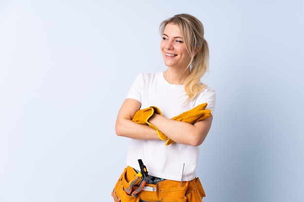 Électricien femme sur fond bleu isolé en riant