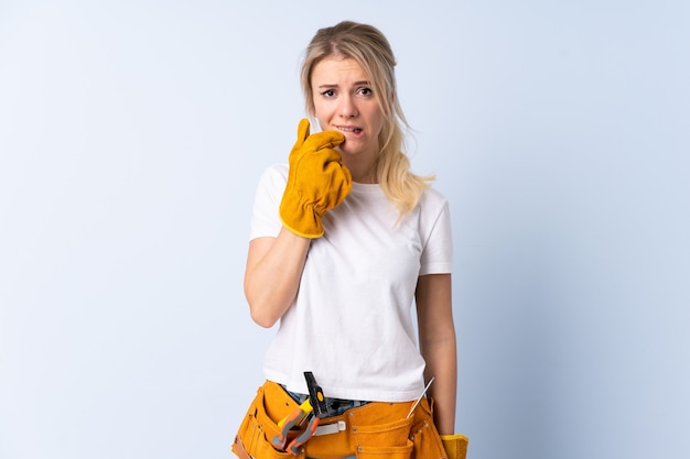 Électricien femme sur isolé bleu nerveux et effrayé