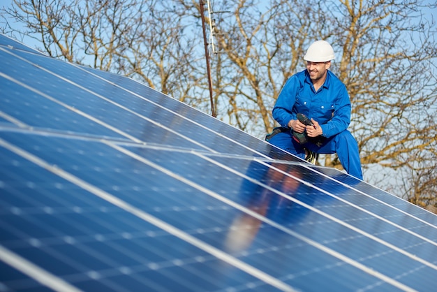 Électricien montant le panneau solaire sur le toit de la maison moderne