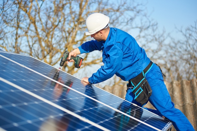 Électricien montant le panneau solaire sur le toit de la maison moderne