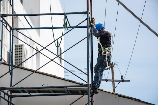 Électricien travaille sur un échafaudage extérieur.