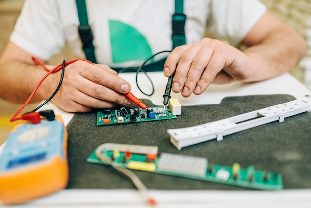 Électricien en uniforme vérifie la puce, bricoleur