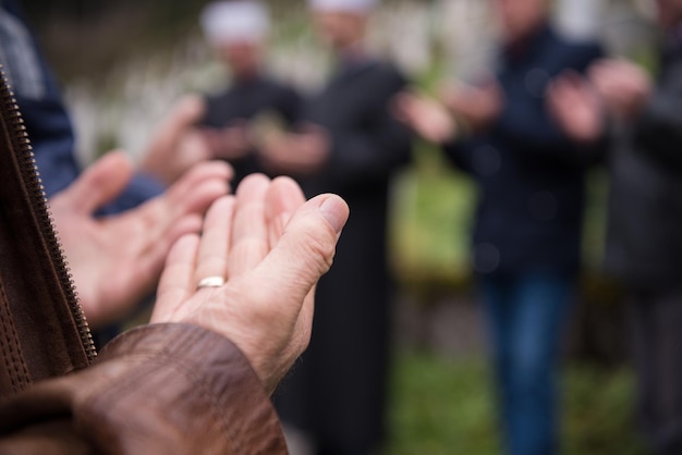 lecture du livre sacré du coran par l'imam sur les funérailles islamiques avec des pierres blanches sur fond de cimetière