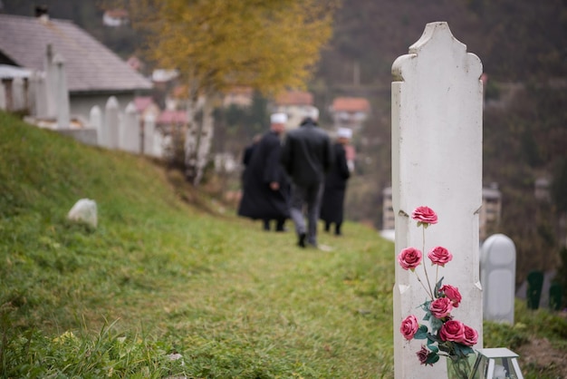 Photo lecture du livre sacré du coran par l'imam sur les funérailles islamiques avec des pierres blanches sur fond de cimetière