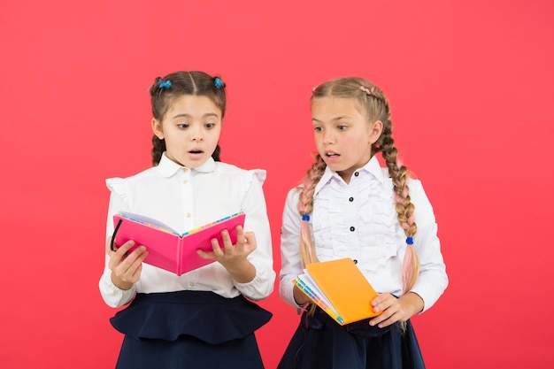 La lecture ouvre des portes Petits enfants lisant des livres sur fond rouge Adorables petites filles apprennent à lire à l'école Élèves mignons lisant pour apprendre des informations importantes