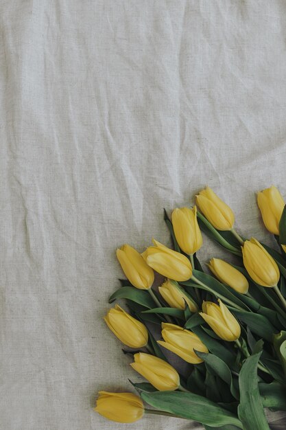 Élégant bouquet de fleurs de tulipes jaunes sur tissu en lin froissé beige neutre Vue de dessus à plat composition florale minimaliste esthétique délicate