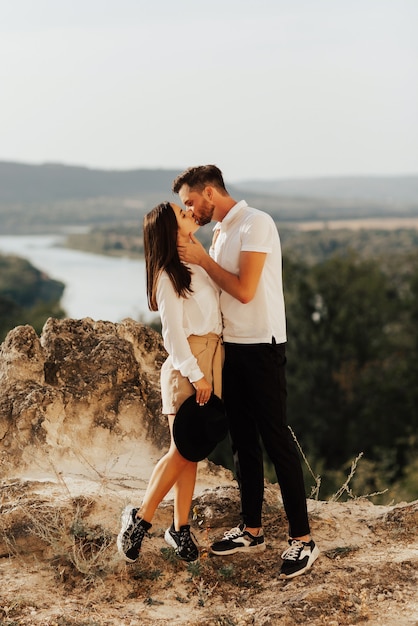 Élégant couple amoureux à pied sur une colline pittoresque étreinte et baiser.