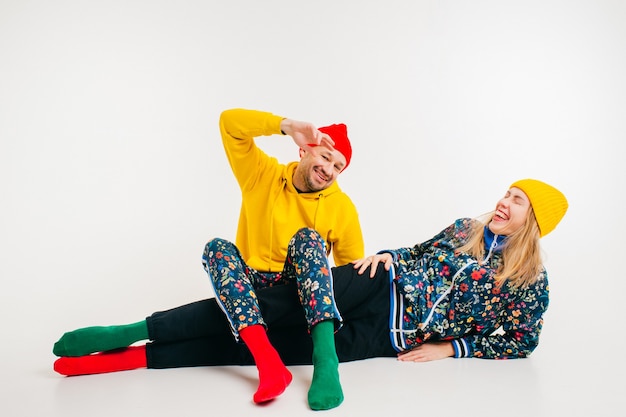 Élégant couple d'homme et femme dans des vêtements colorés posant sur fond blanc