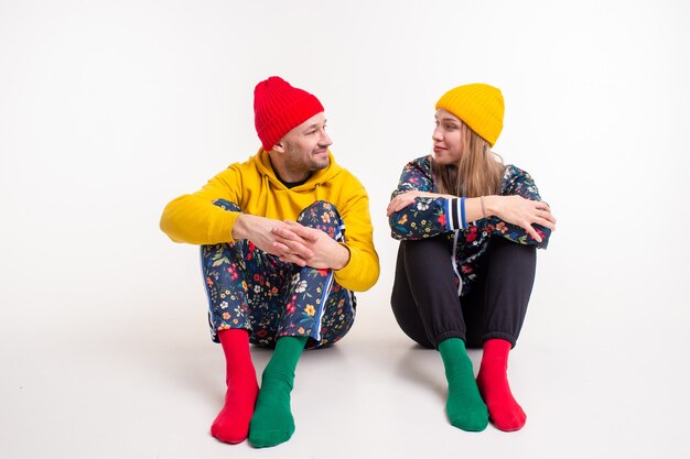 Élégant couple d'homme et femme dans des vêtements colorés posant sur un mur blanc