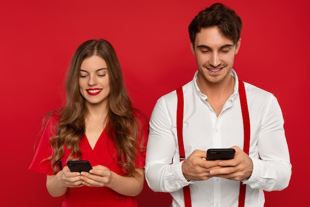 Élégant couple souriant à l'aide de smartphones