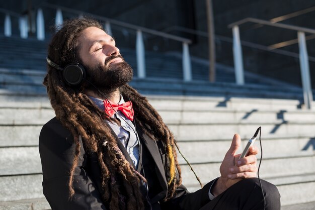 Élégant élégant dreadlocks homme d&#39;affaires écoute musique