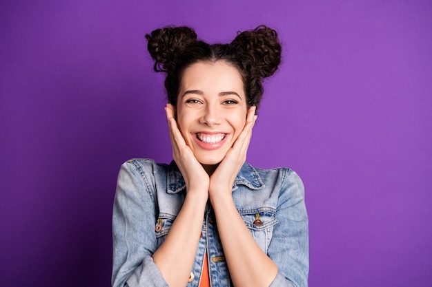 Élégant étudiant aux cheveux bouclés posant contre le mur violet