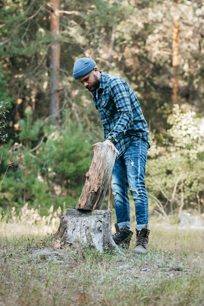 Élégant forestier barbu couper du bois avec une hache