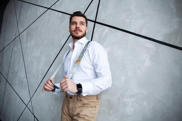 Élégant jeune bel homme. Beau jeune homme debout sur fond gris