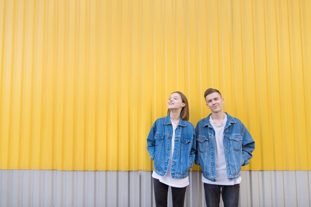 Élégant jeune couple debout sur fond de mur jaune.