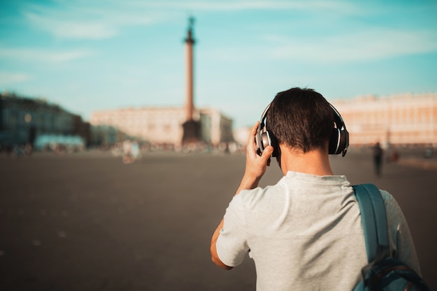 Élégant jeune homme avec sac à dos et un casque sans fil en plein air