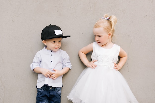 Élégant petit garçon et fille sur mur gris