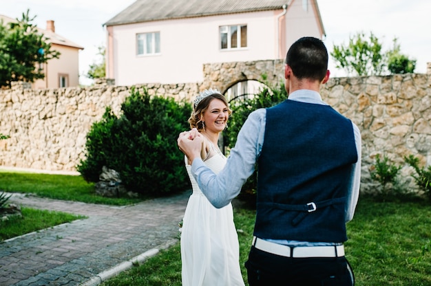 Élégant sourire heureux mariée et le marié se tiennent la main et dansent, courent, vont