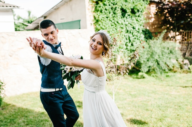 Élégant sourire heureux mariée et le marié se tiennent la main et dansent, courent, vont