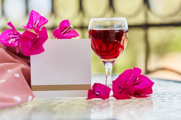 Élégant verre de vin rouge Fleurs roses décoratives de bougainvilliers Maquette de carte postale ou d'invitation