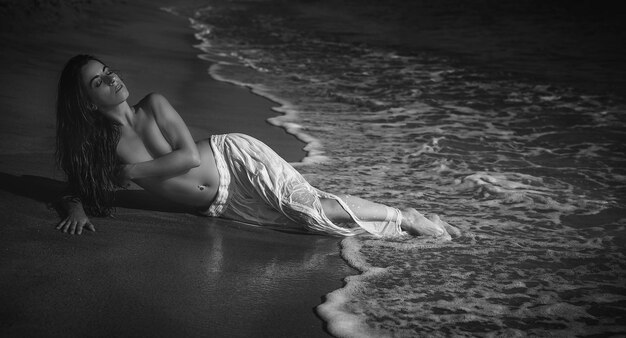 Élégante belle femme brune avec une longue jupe blanche sur la plage en espagne