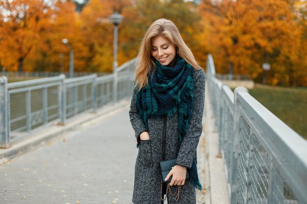 Élégante belle femme en vêtements d'automne à la mode avec foulard marchant à l'extérieur en journée d'automne