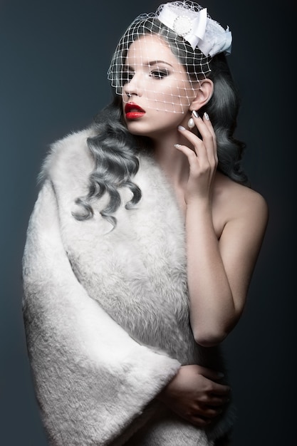 Élégante belle fille avec des boucles d'argent et un voile. Image d'hiver. Beau visage. Photo prise en studio sur fond gris.