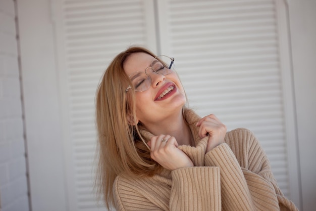 Élégante et belle jeune étudiante avec des lunettes et un chandail surdimensionné beige jeune femme portant un brac