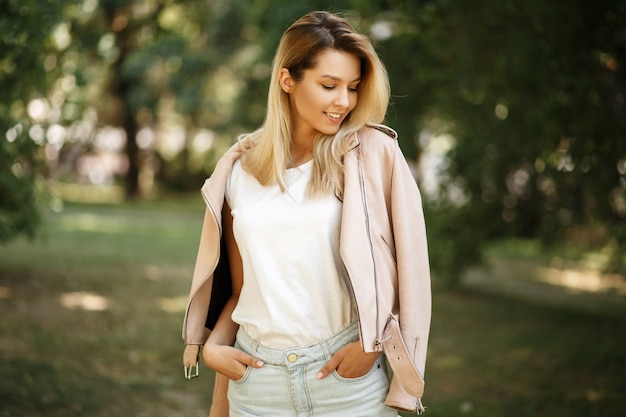 Élégante belle jeune femme heureuse avec un sourire dans des vêtements à la mode dans le parc