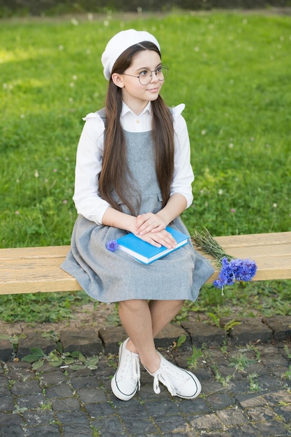 Élégante écolière enfant fille étude avec livre dans le parc, concept d'étudiant français.