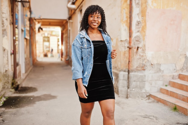 Élégante femme bouclée afro france à la mode posée au jour d'automne en veste de jeans Modèle féminin africain noir