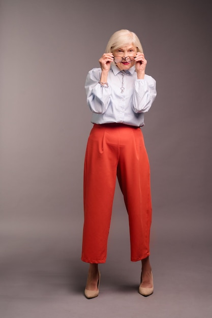 Élégante femme senior en blouse blanche et pantalon rouge