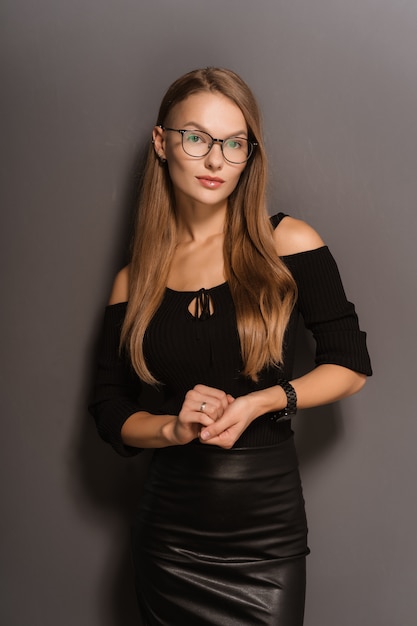 Élégante femme souriante à lunettes sur fond noir