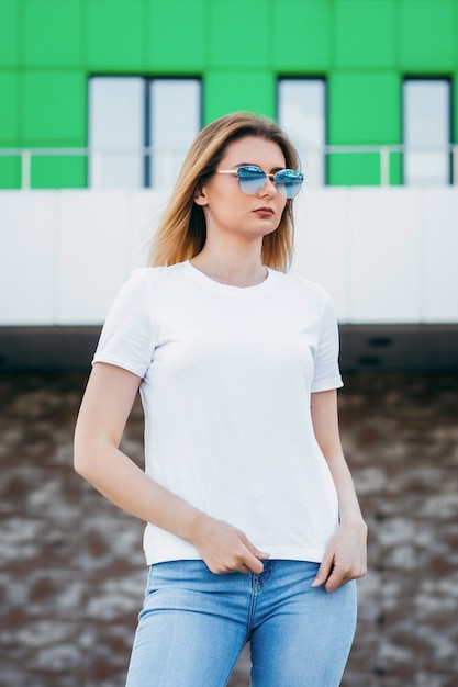 Élégante fille blonde portant un t-shirt blanc et des lunettes