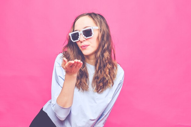 Élégante fille caucasienne dans un t-shirt bleu pâle et des lunettes 8 bits.