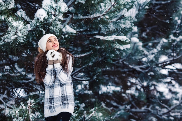 Élégante fille gaie dans un pull dans la forêt d'hiver