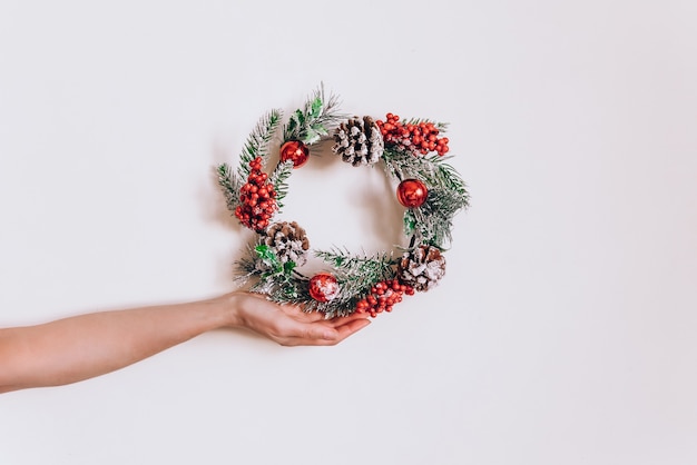 Élégante guirlande de Noël d'épinette dans une main féminine sur un mur léger, le concept de décor pour la nouvelle année