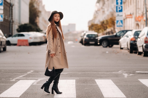 Élégante jeune femme dans un manteau beige dans un chapeau noir dans une rue de la ville. Mode de rue pour femmes. Vêtements d'automne Style urbain.