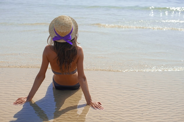 Élégante jeune femme heureuse se détendre sur la plage