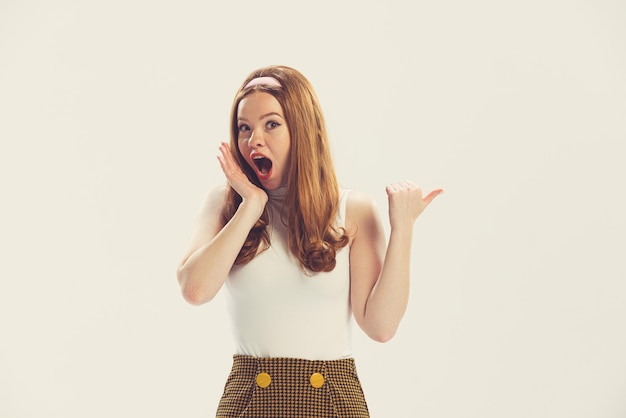 Élégante jeune fille avec une expression faciale choquée posant isolé sur fond de studio blanc Style rétro