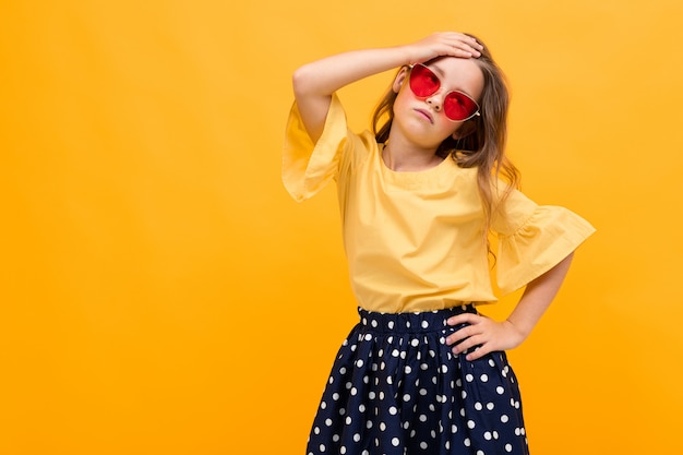 Élégante jeune fille posant isolé sur un fond de studio jaune