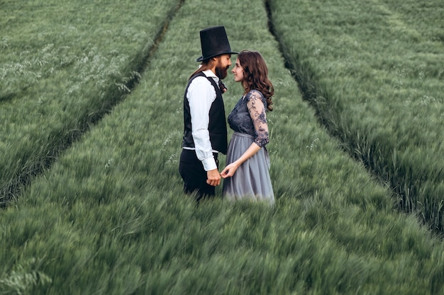 Élégante mariée et le marié marchant et posant sur champ vert